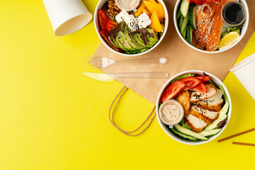 Top view of fresh poke bowls on yellow background