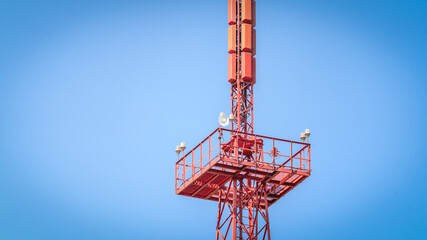 Tower red, cell signal splitter, Antennas and telecommunication equipment. Cell tower with antennas against a blue clear sky, concept of telecommunications equipment.