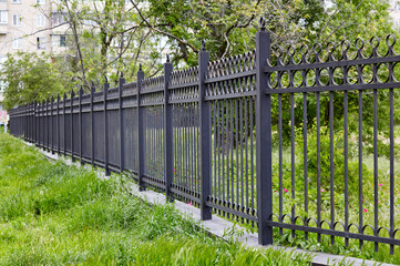 Metal fence in the city park. Decorative black iron guardrail for protection, close up