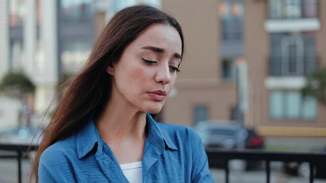 Sad woman with tears welling up in her eyes, feeling heartbroken and down in the city.
