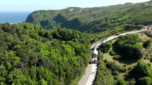 Aerial View Of Tractor Pulling Mobile House Across Road In Chiloe, Chile. This Is called Minga, A South America term meaning - coming together for the common good. Circle Dolly