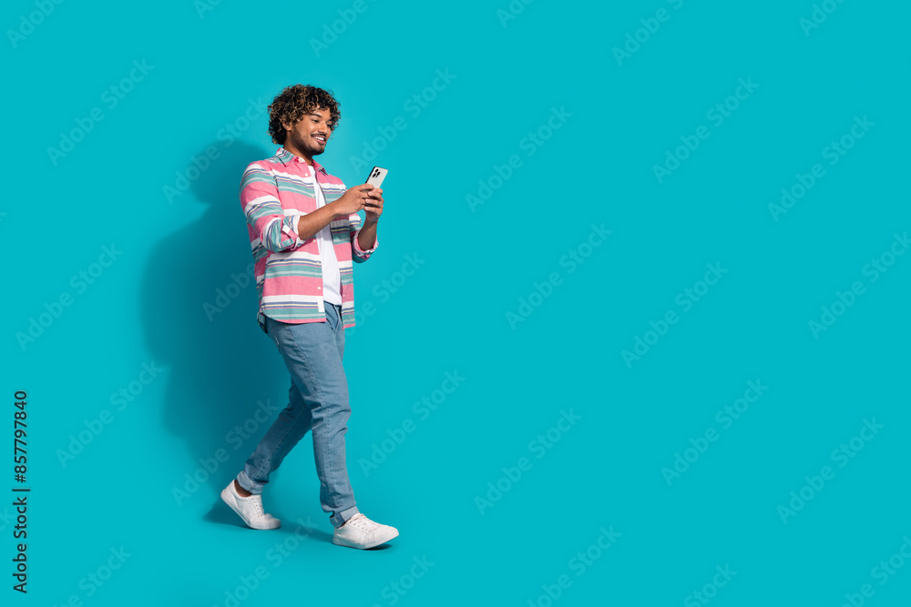 Sticker photo of cheerful young man blogger wear stylish clothes walk empty space isolated on cyan color bac