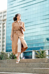 Confident Black Woman Entrepreneur Walking Near Modern Office Building in Stylish Outfit