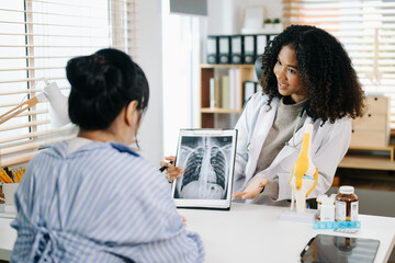 Fototapeta premium Asia female doctor using clipboard is delivering great news talk discuss results or symptoms with female patient