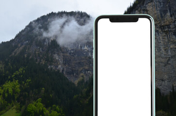 Mobile phone with empty screen against mountain landscape. Space for design
