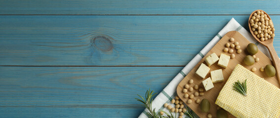 Delicious tofu, soybeans, olives and rosemary on blue wooden table, top view with space for text. Banner design