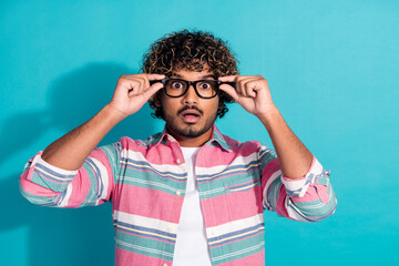 Photo of impressed shocked man wear trendy striped clothes hold glasses isolated on cyan color...