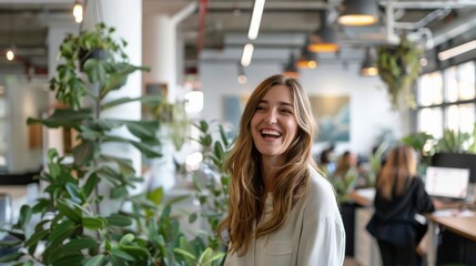 A smiling woman stands in a modern office space decorated with lush plants, suggesting a harmonious blend of nature and work, uplifting mood and productivity.