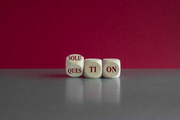 Question and solution symbol. Turned a wooden cube and changes the word 'question' to 'solution'. Beautiful gray table, pink background. Business question and solution concept