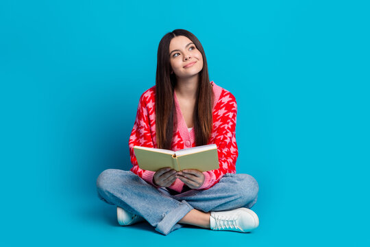 Full size photo of positive smart woman dressed knitwear cardigan read book dreamy look empty space isolated on blue color background