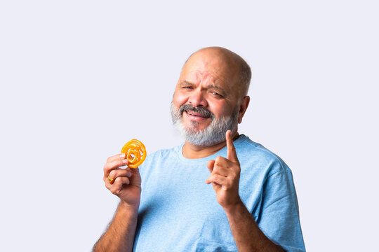 Asian senior matured elderly man eating jilapi or jalebi, a traditional indian sweet food