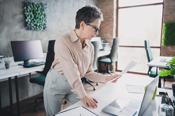 Photo of attractive good mood age lady agent dressed formal shirt reading documents indoors...