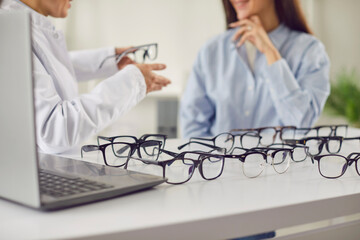 Doctor ophthalmologist consulting a patient during a visit to prescribe eyeglasses. Focused on eye...