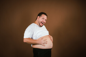 Sports, diet and healthy lifestyle. Funny fat man posing on a brown background.