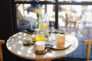 Delicious breakfast for two at the luxury hotel with fresh orange juice, vegan cake, coffee cappuccino on wooden table. Cafe brunch. Top view.