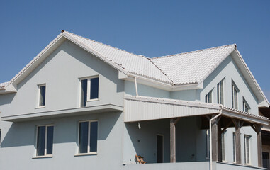 Enerergy efficiency moder house under construction with white roof tiles, white rain gutters and  white facade walls.