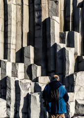 A man is standing in front of the Gardar basalt columns, Iceland