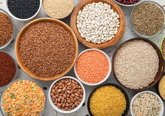 Top view of bowls with various healthy cereals. Bulgur,beans,quinoa,pea,couscous and hemp with chickpea and buckwheat seed on light kitchen background.Macro.