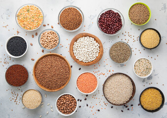 Top view of bowls with various healthy cereals. Bulgur,beans,quinoa,pea,couscous and hemp with chickpea and buckwheat seed on light kitchen background.Macro.