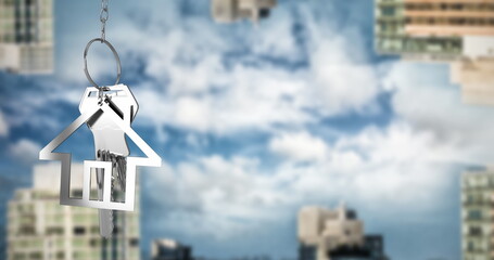 Image of hanging house keys against inverted tall buildings against clouds in the blue sky