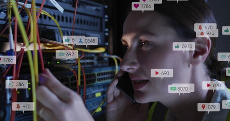 Image of social media icons over caucasian female engineer talking on smartphone at server room