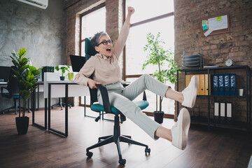 Photo of lucky good mood age lady agent dressed formal shirt rising fist having fun indoors...