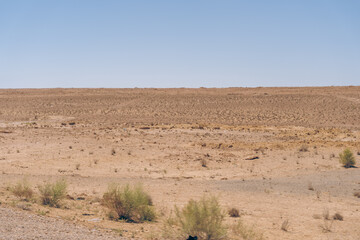 A desert landscape with a clear blue sky. The sky is very bright and the sun is shining