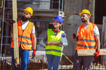 Two construction workers carrying bars at a building site - people at work concepts inside the building.