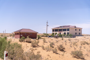 A small house is in the middle of a desert. The house is surrounded by a lot of dry grass and dirt