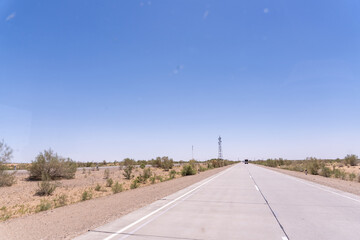 A road with a tall tower in the distance. The sky is clear and blue