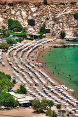 Eine Badebucht mit Sonnenschirmen, Gästen und türkisfarbenem Wasser in Lindos, einer...