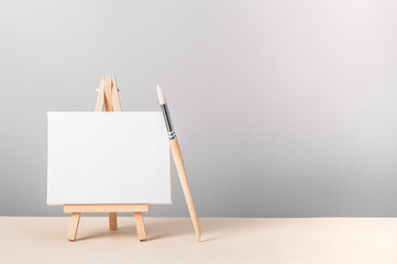 Miniature canvas on an easel and a brush for painting. Art creativity concept with copy space.