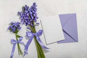 A bouquet of lavender-colored spring scilla and a bouquet of phlox, a lavender envelope and a blank...