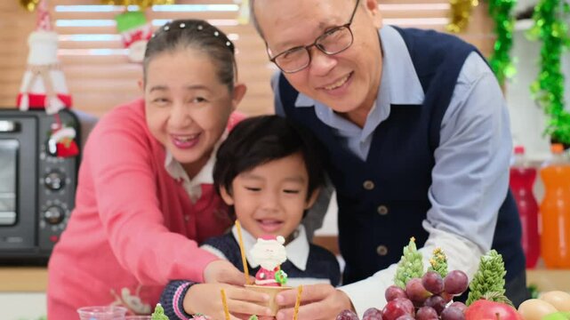 Happy Asian family spending times to prepare Chritsmas and Happy news year Celebrete. kids parent and grandparent doing ginger breads and bakery enjoy and dancing in kichen at home