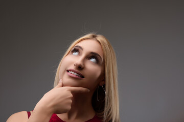 Fototapeta premium Young woman touching chin thinking looking up to empty space bac
