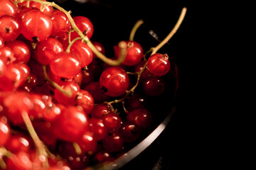 Red currants in a plate on a black background.red currant isolate.Berry concept