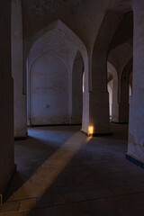A dark room with a candle in the middle of the floor. The candle is lit and casts a shadow on the floor