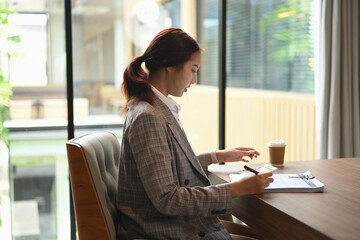 Side view of financial accountant sitting at desk working reviewing financial data or accounting statistics