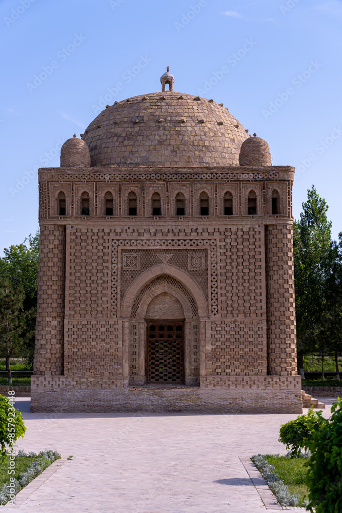 Wall mural A large building with a dome on top. The building is brown and has a lot of arches. The building is in a courtyard with trees and bushes