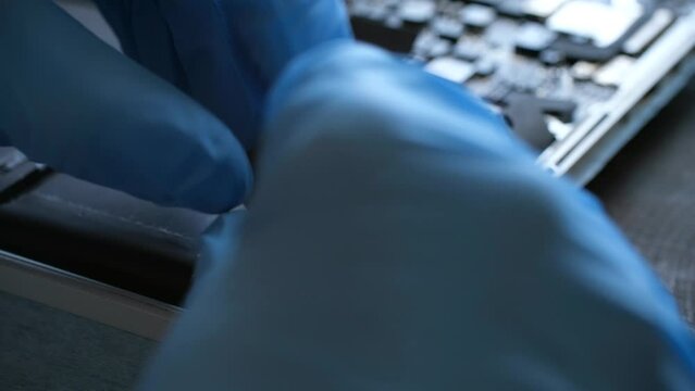 Technician in gloves carefully uninstalls old battery block in laptop. Man ensures connection secure and properly aligned with professional approach. Laptop repair service.