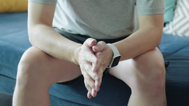 Closeup hands of stressed nervous man sitting at sofa