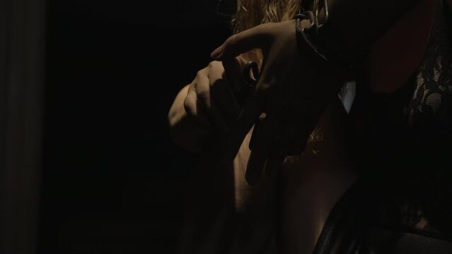 A woman with long hair is shackled in chains with a lock hanging from them. She struggles to free herself and eventually succeeds.