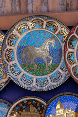 A collection of plates with a horse on them. The plates are colorful and ornate, and they are displayed on a blue background. The horse is the main focus of the plates