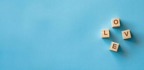 Horizontal image of wooden cubes with text "love" on isolated light blue background, copy space for text. For banner, design, presentation, slide, social media, profile, LinkedIn, cover, thumbnail