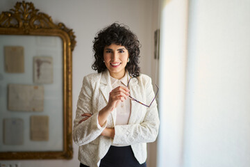 A woman in a white jacket and black skirt is smiling