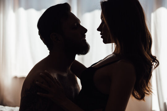 Couple kissing in darkness. Young woman and man embracing in bedroom. Dating concept