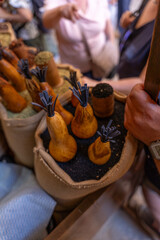 A person is holding a bag of vegetables, including squash, and pointing to them. The scene appears to be a market or a gathering of people