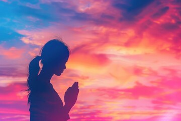 Fototapeta premium A silhouette of a woman praying in front of a stunning sunset, perfect for spiritual or inspirational themes