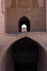 Fototapeta premium A brick archway with a small window in the middle. Scene is somber and mysterious