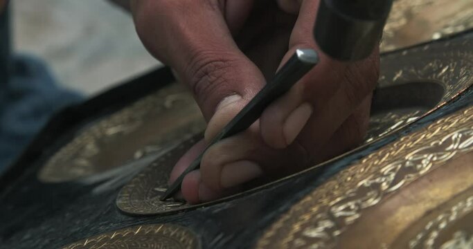 A master embosser creates a pattern on a copper plate using ancient technologies.